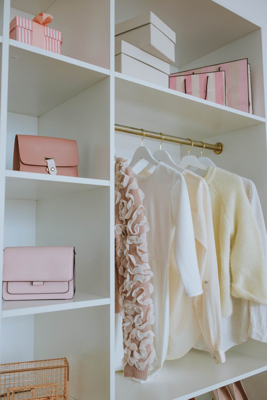 Photo d'un dressing de femme avec des sacs à main, des vêtements. Les couleurs sont dans le rose, blanc, beige. le style vestimentaire est romantique et féminin. Envie de mode, d'être fashion, tendance.